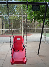 写真:背もたれとフットレスト付きのブランコ。頭上の梁に小さな看板がぶら下がる。