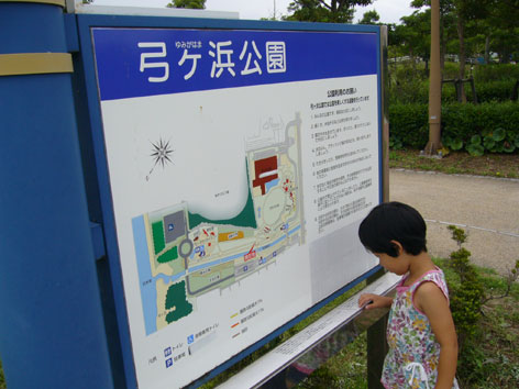 写真:入口の案内板。下部に設けられた桟を指でなぞる女の子