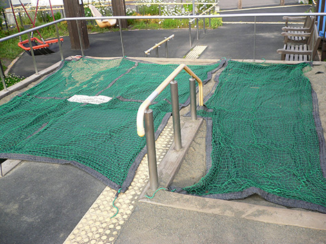 写真:砂場。園路からほぼフラットでアクセスできる。砂場の表面に猫避けのネットカバーがかけられている
