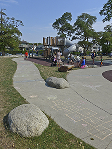 写真:複合遊具周辺の地面。園路にはカラフルなチョークで子どもが描いた絵や石蹴り遊びの枠。