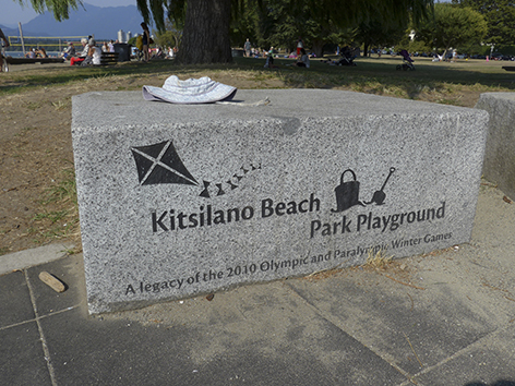 写真:岩を直方体に切り出したベンチ。側面には公園の名前と、凧揚げや砂遊びのイラストが刻まれている。